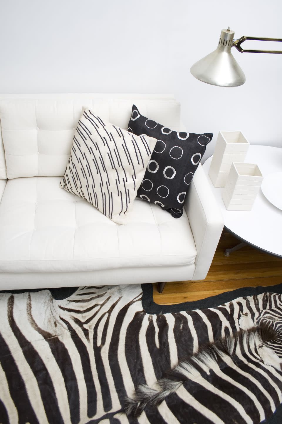 white condo with danish couch, midcentury floor lamp and antique zebra rug