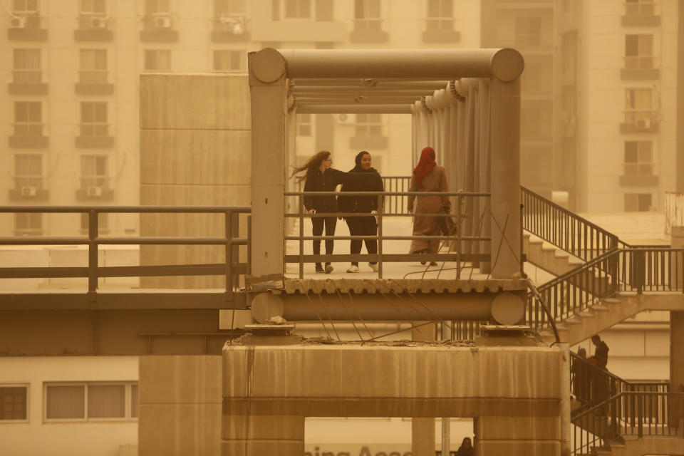 Pedestrians cross a bridge during a sandstorm in Cairo, Egypt, Wednesday, Jan. 16, 2019 as a thick sandstorm cloaked parts of the Middle East. A harsh weather front brought sandstorms, hail and rain to parts of the Middle East, with visibility down in the Egyptian capital as an orange cloud of dust blocked out the sky. (AP Photo/Amr Nabil)
