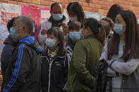 Residents wearing face masks to help curb the spread of the coronavirus gather at a vaccination site as they wait to receive booster shots against COVID-19, in Beijing, Monday, Oct. 25, 2021. A northwestern Chinese province heavily dependent on tourism closed all tourist sites Monday after finding new COVID-19 cases. (AP Photo/Andy Wong)