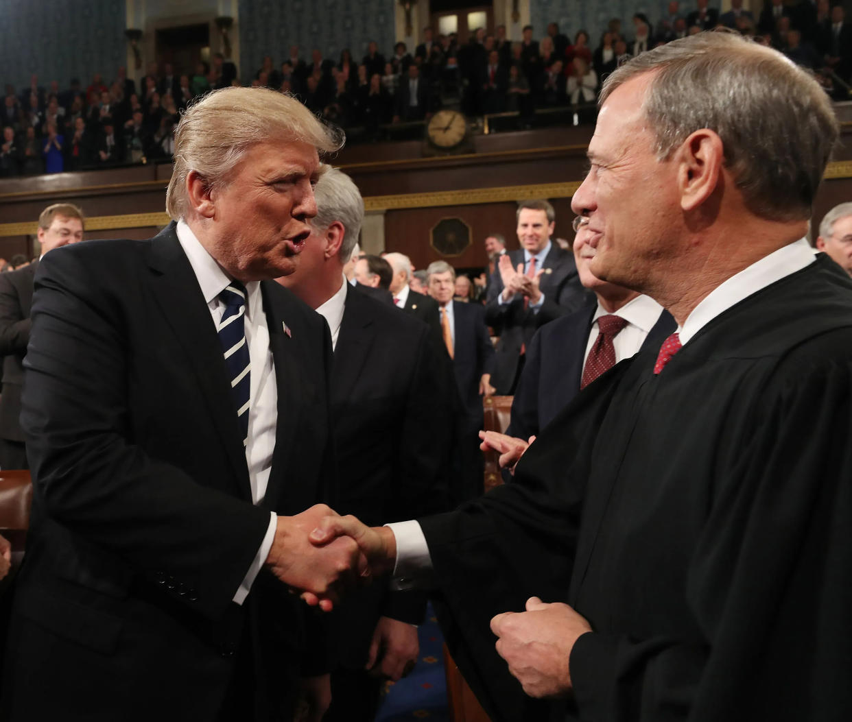 Chief Justice John Roberts, right, and then-President Donald Trump shake hands at a State of the Union address,