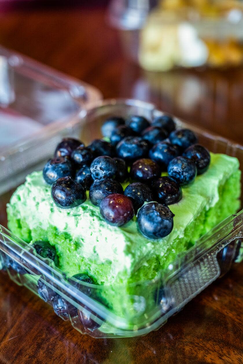 A slice of green cake topped with blueberries