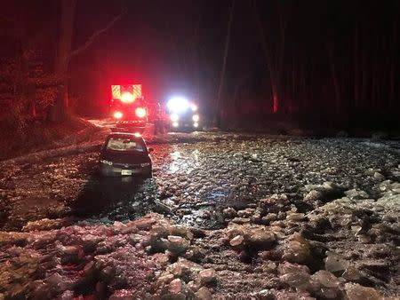 Firefighters rescue three people after a car was stuck in icy water in Boyds, Maryland, U.S., in this January 1, 2018 image by Montgomery County Fire and Rescue Service obtained from social media. Picture taken January 1, 2018. Montgomery County Fire and Rescue Service/Social Media/via REUTERS