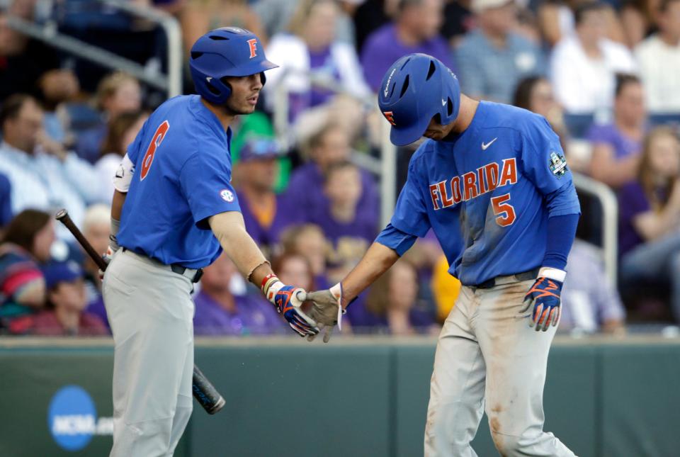 Florida's Dalton Guthrie (5) is greeted by Jonathan India (6) after scoring on a ground rule double in the fourth inning of Game 1 of the NCAA College World Series baseball finals against LSU in Omaha, Neb., Monday, June 26, 2017. (AP Photo/Nati Harnik)