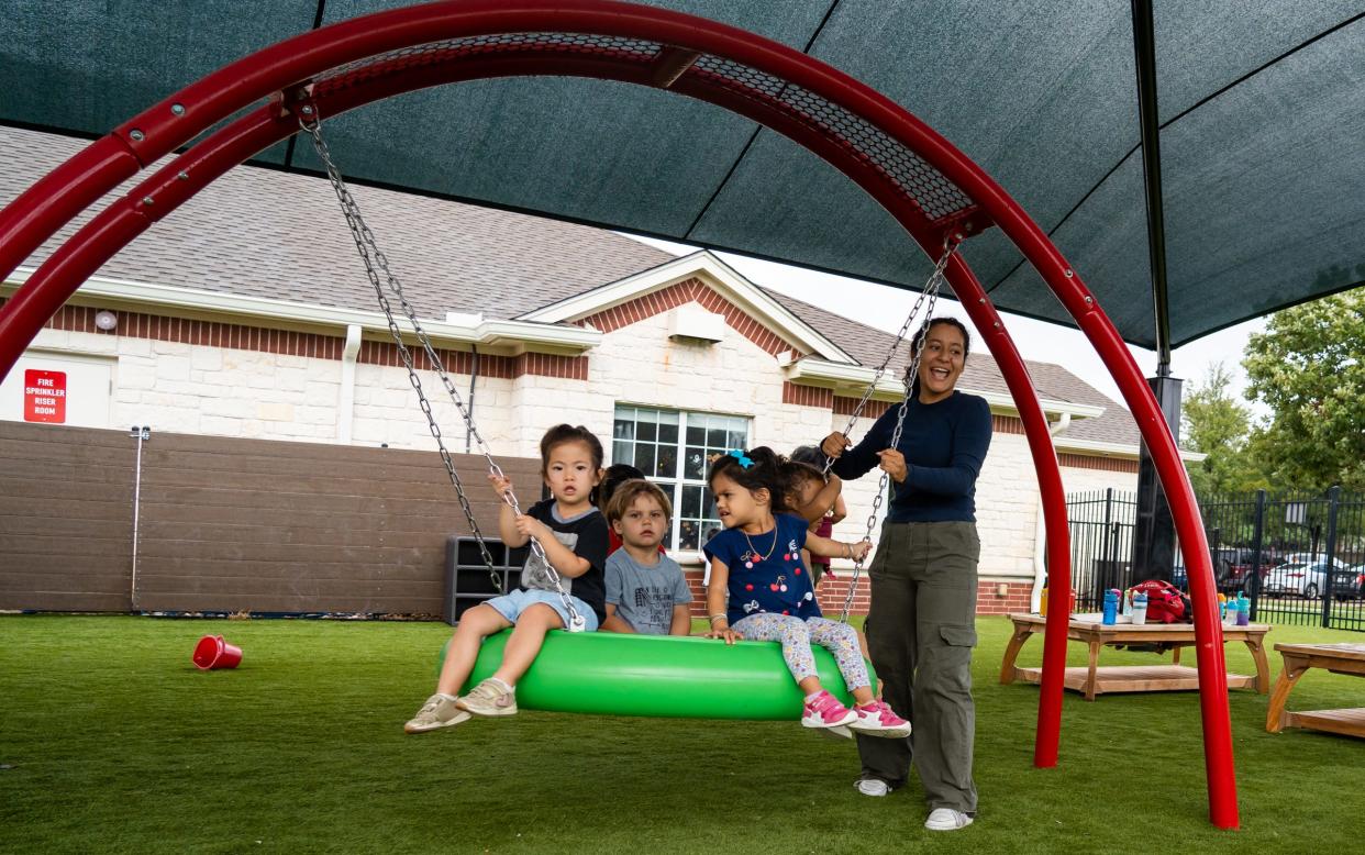 Teacher Rianna Muniz pushes kids on a swing at the Circle C Childhood Development Center last fall. The Travis County Commissioners Court has preliminarily voted to put on the November ballot a proposed tax rate increase to help fund early childhood education programs.