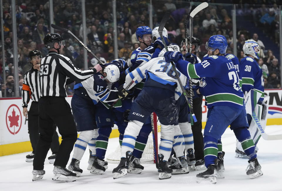 Vancouver Canucks' Tyler Myers grabs Winnipeg Jets' Adam Lowry as the teams get into a scuffle after the whistle during the second period of an NHL hockey game in Vancouver, on Saturday, Dec. 17, 2022. (Darryl Dyck/The Canadian Press via AP)