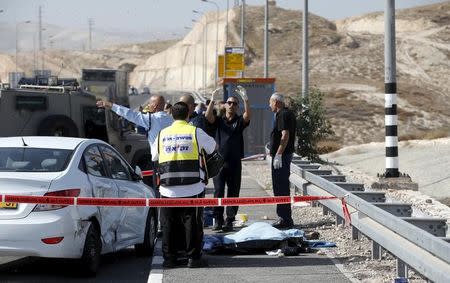 An Israeli police officer gestures beside the covered body of a Palestinian, who police said attempted a ramming attack, near the West Bank Jewish settlement of Kfar Adumim November 22, 2015. REUTERS/Ronen Zvulun