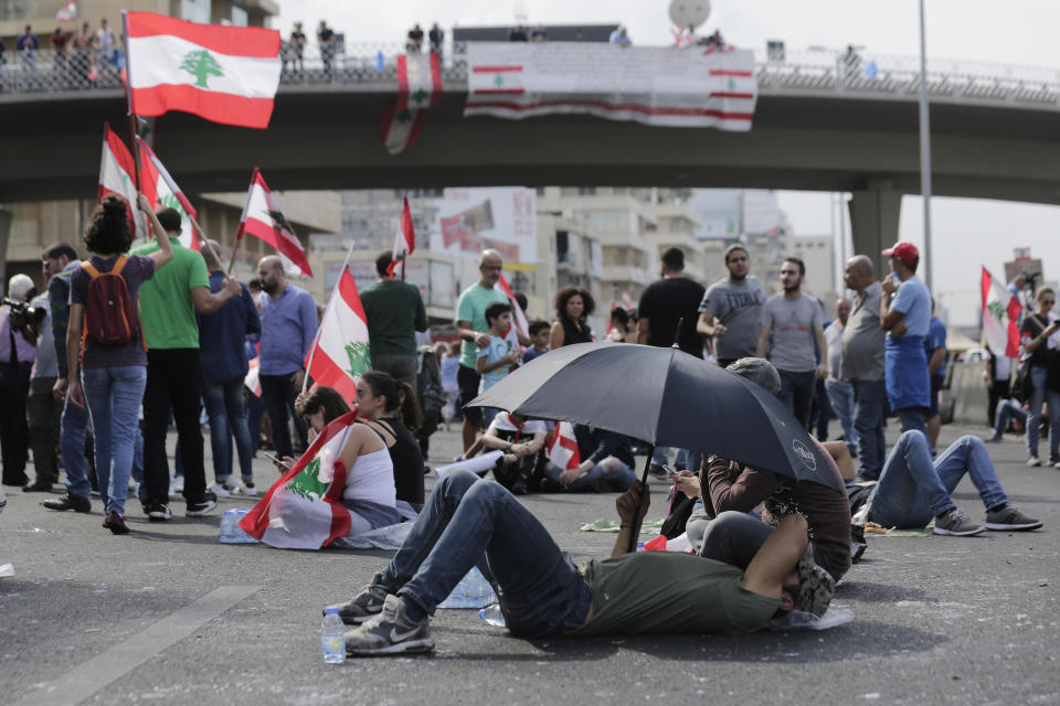 Anti-government protesters block a road while waiting for Lebanon's President Michel Aoun to address the nation during a protest in the town of Jal el-Dib north of Beirut, Lebanon, Thursday, Oct. 24, 2019. Aoun has told tens of thousands of protesters that an economic reform package put forth by the country's prime minister will be the "first step" toward saving Lebanon from economic collapse. (AP Photo/Hassan Ammar)