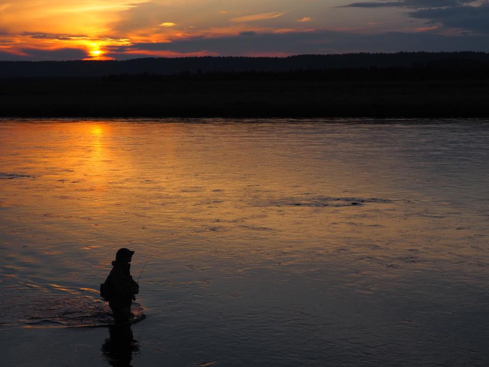 Wildfire smoke makes for a dramatic sunset around this fly fisher in Idaho during the summer of 2021.