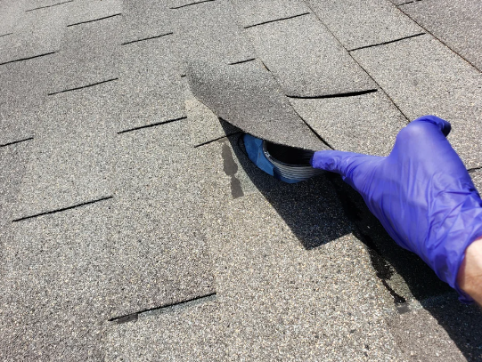 hand lifting up the shingle that's covering the ventilation