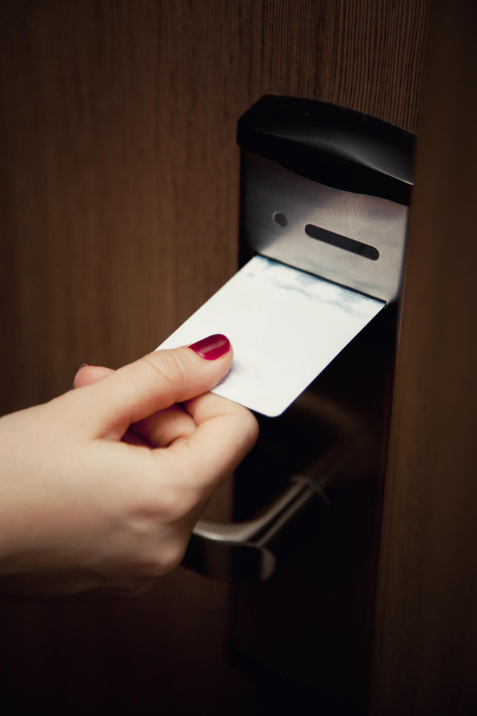 Close-up of a person's hand inserting a keycard into a door lock