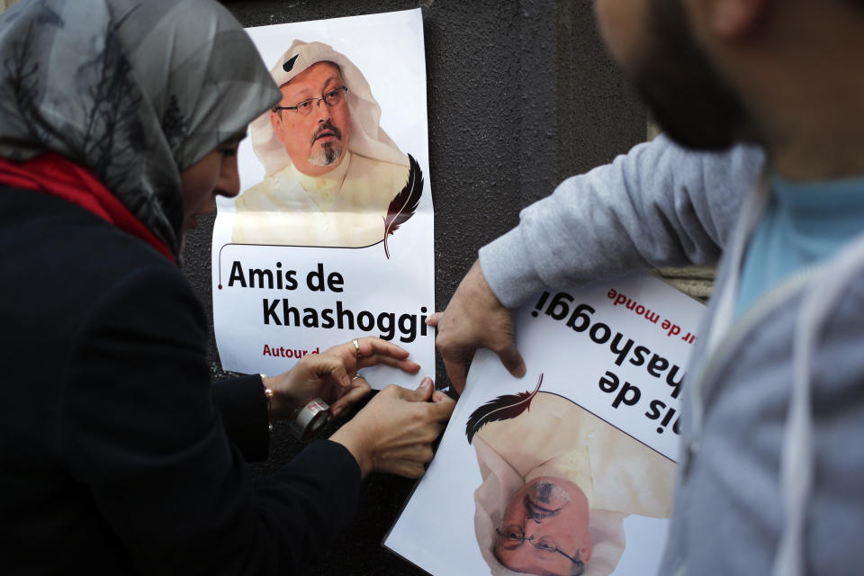 Activists sticks a portrait reading "Friends of Khashoggi around the world" as part of a protest closed to the Saudi Arabia embassy, in Paris, Thursday, Oct. 25, 2018. Saudi prosecutors say the killing of journalist Jamal Khashoggi was planned, state-run media reported Thursday, reflecting yet another change in the shifting Saudi Arabian account of what happened to the writer who was killed by Saudi officials in their Istanbul consulate. (AP Photo/Francois Mori)