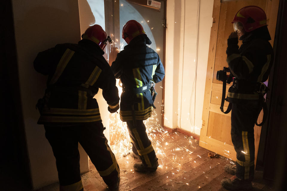 A firefighter uses a rotary saw to open an apartment door to check on residents stuck inside in Odesa, Ukraine, Sunday, July 23, 2023, following Russian missile attacks. (AP Photo/Jae C. Hong)