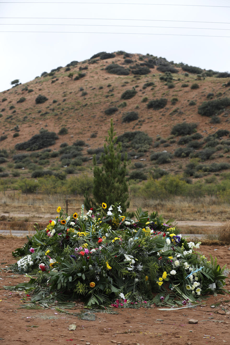 Freshly dug graves that contain the remains of Rhonita Miller and four of her young children are overspread with flowers a day after their burials, at the cemetery in Colonia LeBaron, Mexico, Saturday, Nov. 9, 2019. U.S. citizens living in a small Mexican farming community established by their Mormon ancestors are trying to decide whether they should stay or leave after burying some of the nine American women and children slaughtered this week in a drug cartel ambush. (AP Photo/Marco Ugarte)