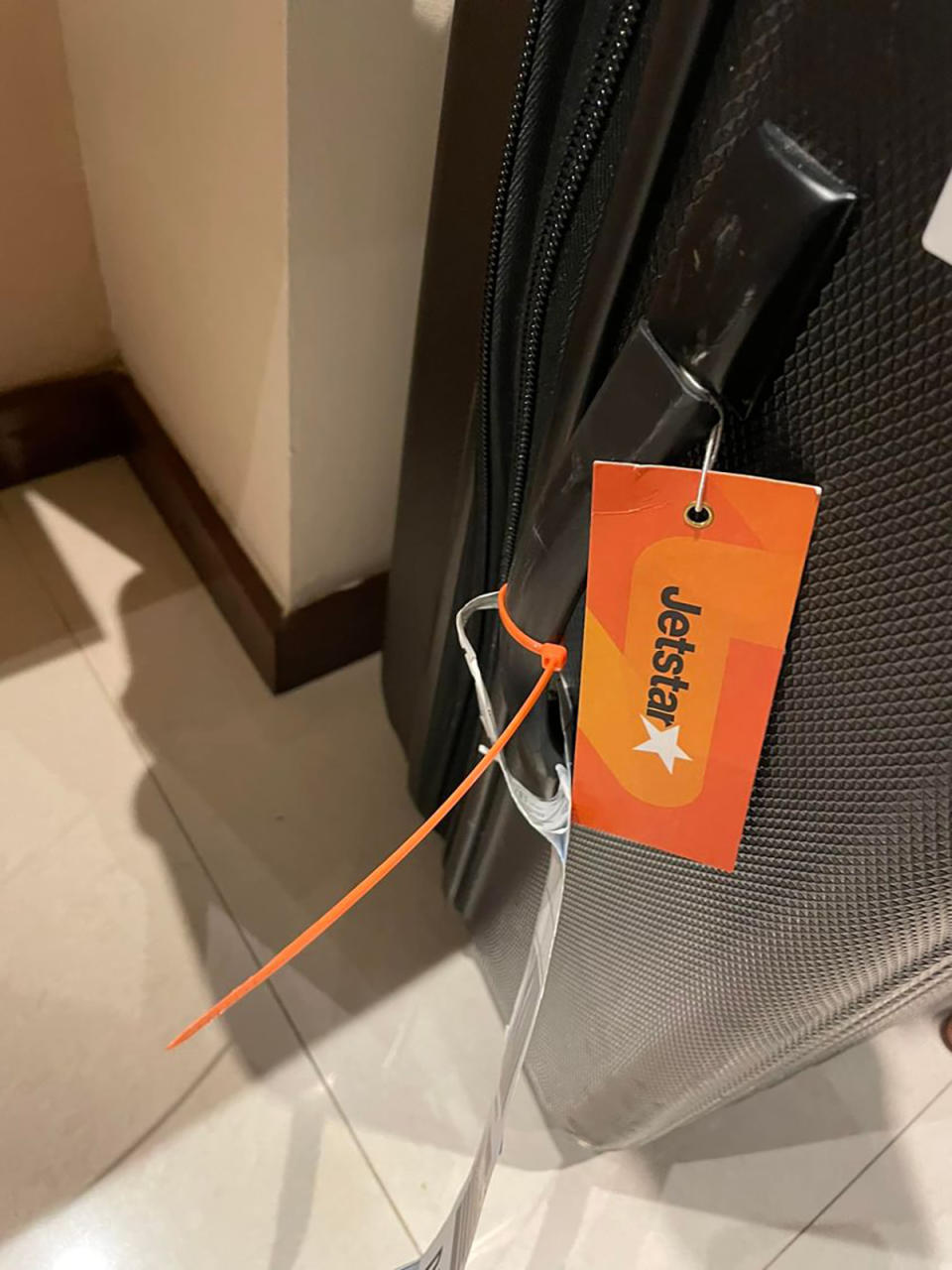 Suitcase with orange cable tie and Jetstar tag on handle, pictured at Bali hotel