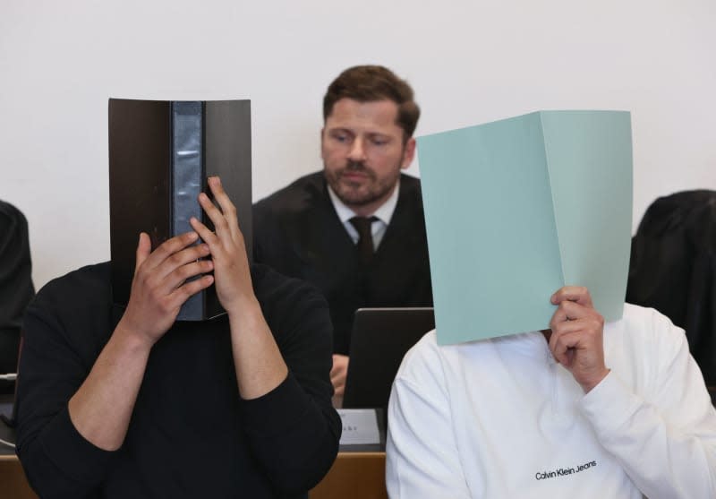 The main defendant (R) sits in the dock in a courtroom alongside other defendants in front of lawyer Harald Stehr (C). On 11 November 2023, the man is alleged to have set off a firecracker in the visitors' block during the Bundesliga match between FC Augsburg and TSG 1899 Hoffenheim. Karl-Josef Hildenbrand/dpa