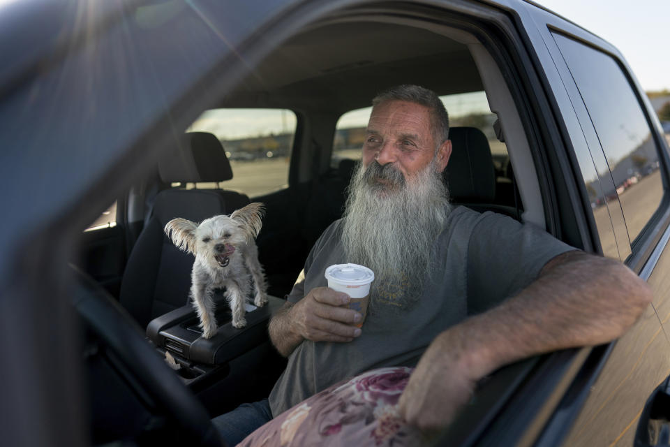 Joe Smith drinks a cup of White Castle coffee with his dog Presley in his truck after work in Columbus, Ohio, Tuesday, Oct. 24, 2023. Smith did not picture raising his granddaughter, but when his daughter's substance use disorder meant she couldn't care for her child, that's where Smith and his late wife found themselves nineteen years ago. (AP Photo/Carolyn Kaster)