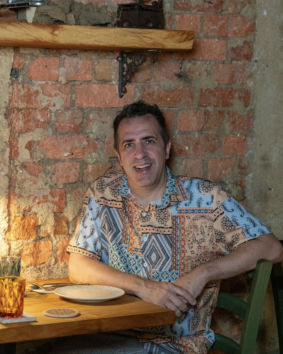Chef Antonio Miscellaneo sitting at a table in his restaurant, La Bottega Enoteca.