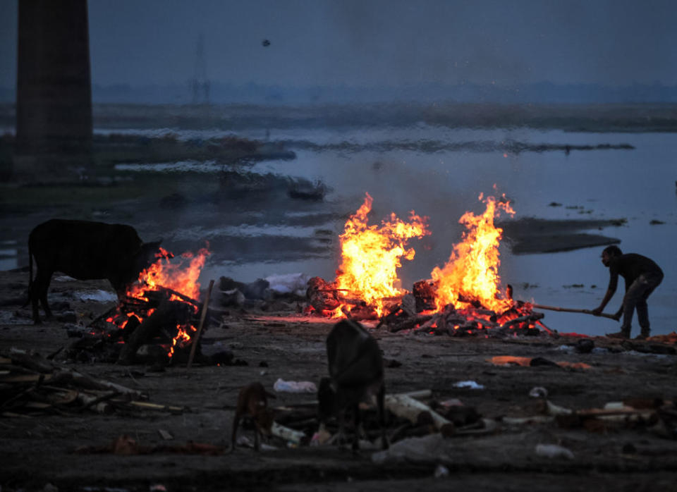 A crematorium worker cremates the unclaimed bodies of people who were thought to have died of Covid in a mass crematorium ground, on the banks of Ganges River on May 5. Source: Getty