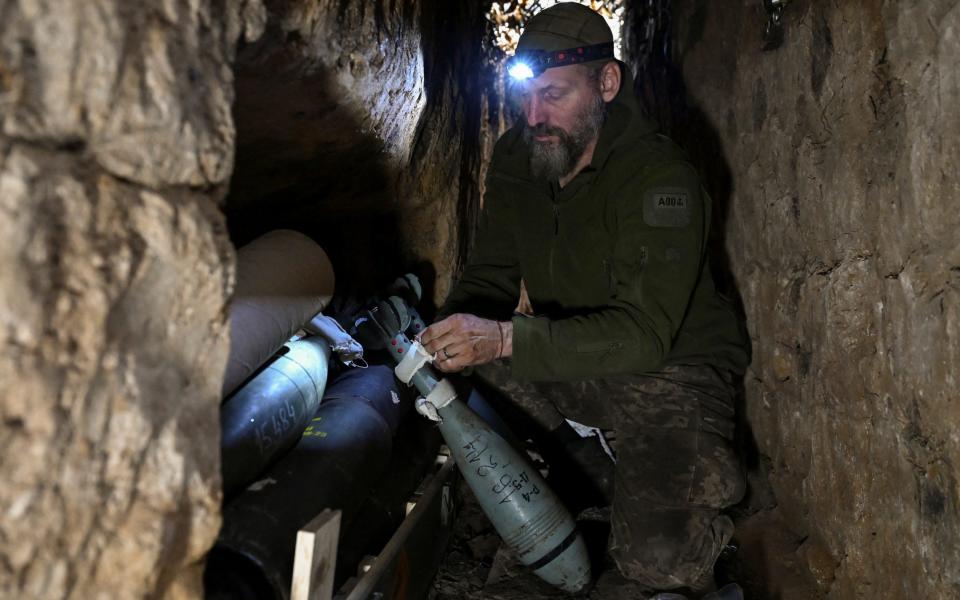 A Ukrainian serviceman prepares mortar shells inside a dugout at a position in a front line
