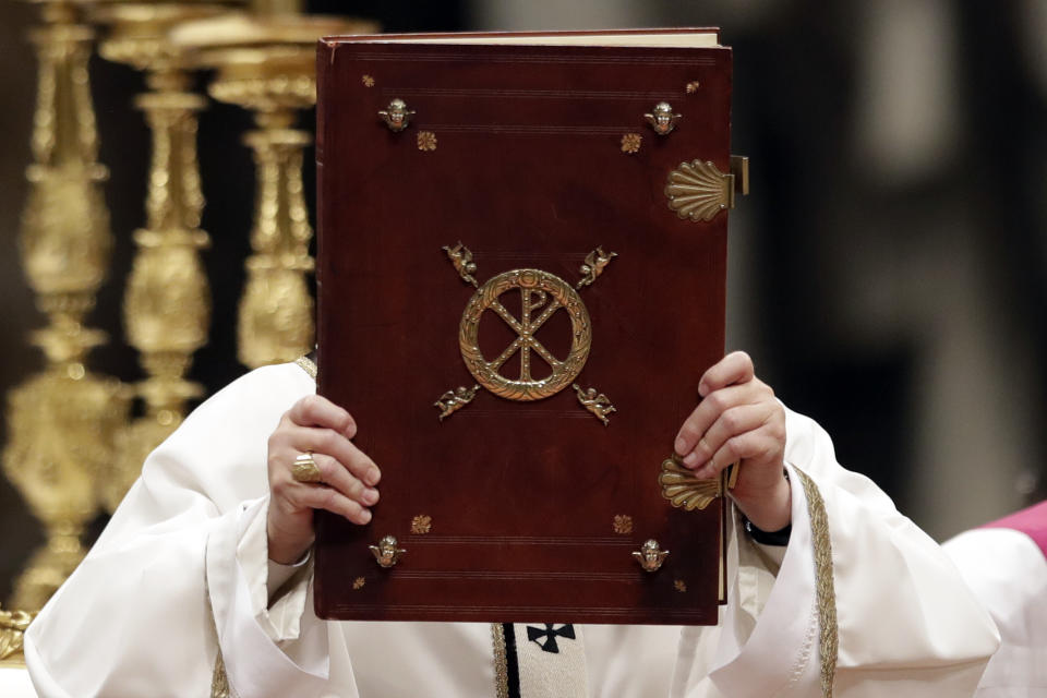 FILE - Pope Francis holds the book of the Gospels as he celebrates the Christmas Eve Mass in St. Peter's Basilica at the Vatican, Saturday, Dec. 24, 2016. (AP Photo/Alessandra Tarantino, File)