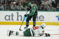 Dallas Stars defenseman Esa Lindell (23) controls the puck as Minnesota Wild center Connor Dewar (26) goes down during the first period of an NHL hockey game in Dallas, Sunday, Dec. 4, 2022. (AP Photo/LM Otero)