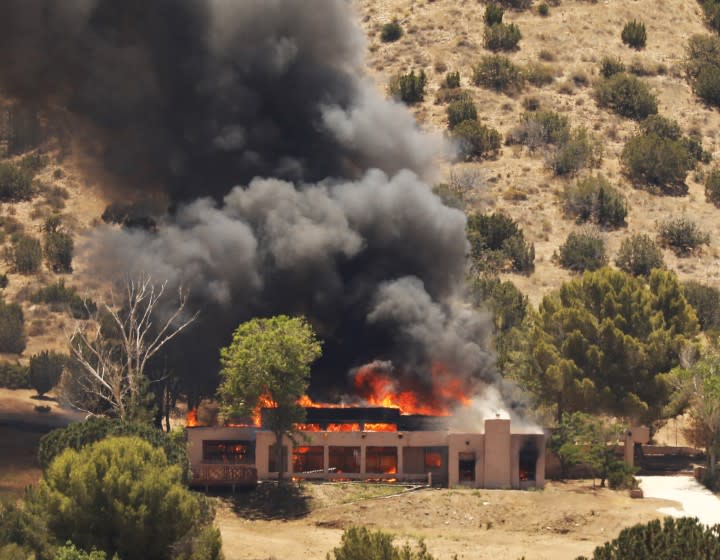 ACTON, CA - JUNE 01: LA County fire helicopter makes water drops on a burning home located at 2602 W. Bent Spur Dr, in Acton which police believe may be involved as the home of the shooter as LA County Sheriff's investigate LA County Fire Station 81 located at 8710 Sierra Hwy in Agua Dulce where one firefighter was killed and one injured. Acton on Tuesday, June 1, 2021 in Acton, CA. (Al Seib / Los Angeles Times).