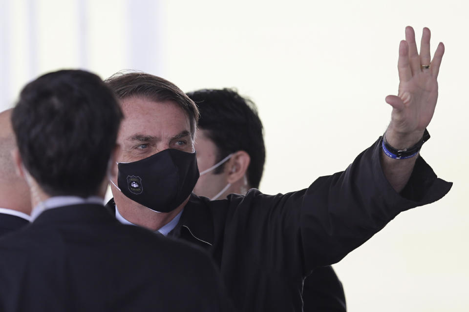 Brazil's President Jair Bolsonaro, wearing a face mask amid the new coronavirus pandemic, waves to supporters as he leaves the official residence of Alvorada palace, in Brasilia, Brazil, Monday, May 25, 2020. (AP Photo/Eraldo Peres)