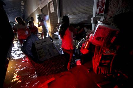 People carry looted goods as they walk through a flooded street in Acapulco September 18, 2013. REUTERS/Jacobo Garcia