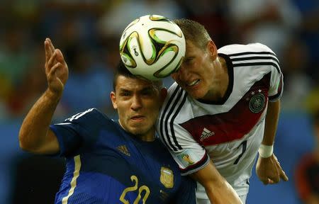 Argentina's Sergio Aguero jumps for the ball with Germany's Bastian Schweinsteiger during their 2014 World Cup final at the Maracana stadium in Rio de Janeiro July 13, 2014. REUTERS/Eddie Keogh