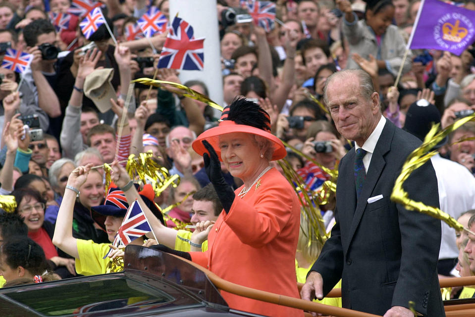 Queen Elizabeth II and her husband, Prince Philip, ride along The Mall in an open-top car as they return to watch a parade outside Buckingham Place. The parade, which lasted more than three hours, included processions by the Notting Hill Carnival, the Commonwealth and children from the Chicken Shed Theatre Company. The Queen is waving to the crowds that have gathered to greet her. (Photo by © Pool Photograph/Corbis/Corbis via Getty Images)