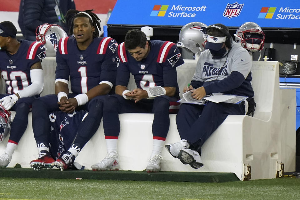 New England Patriots quarterbacks Cam Newton, left, and Jarrett Stidham sit on the bench with offensive coordinator Josh McDaniels, right, in the second half of an NFL football game against the San Francisco 49ers, Sunday, Oct. 25, 2020, in Foxborough, Mass. (AP Photo/Steven Senne)