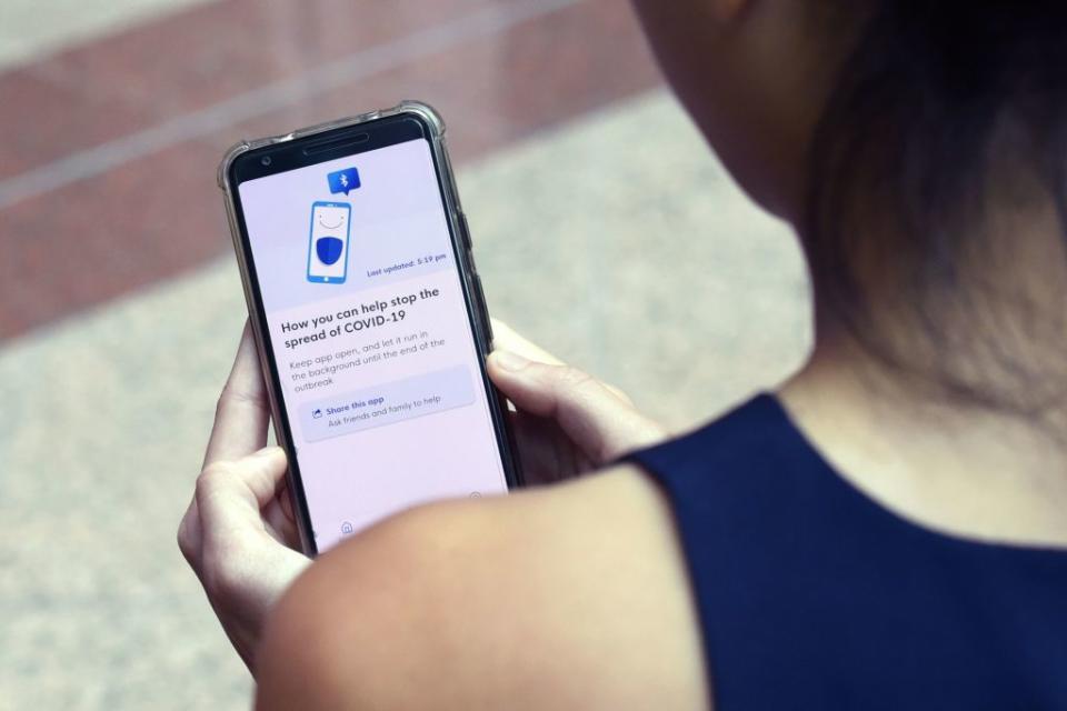 A government staff member demonstrates Singapore's new contact-tracing smartphone app called TraceTogether. Source: Getty