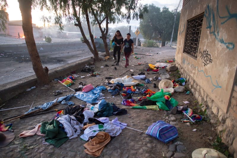 Women walk past belongings of supporters of Bolivia's former President Evo Morales after clashes in Sacaba