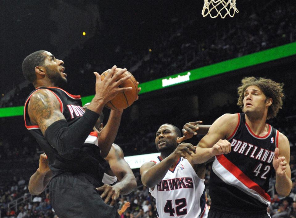 Portland Trail Blazers high scorer LaMarcus Aldridge, left, shoots over Atlanta Hawks' Elton Brand (42) and Portland teammate Robin Lopez in the second half of their NBA basketball game Thursday, March 27, 2014, in Atlanta. Portland won 100-85. (AP Photo/David Tulis)