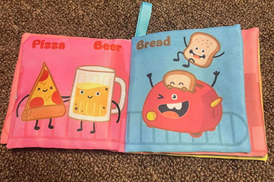 Inside of a baby's book with cartoon food items 'pizza', 'beer' and 'bread'