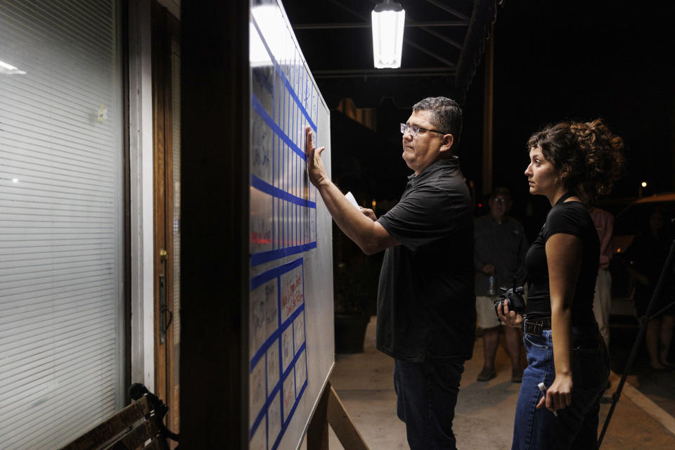 Uvalde Leader-News journalists Pete Luna and Sofi Zeman update the white board with the election results during a watch party held outside of the newspaper Tuesday evening, Nov. 7, 2023, in Uvalde, Texas. Former mayor Cody Smith won the Uvalde mayoral election over Kimberly Mata-Rubio and Veronica Martinez. (Sam Owens/The San Antonio Express-News via AP)