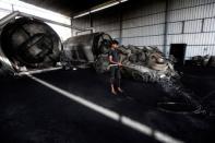 A labourer sprays water around a reactor at a pyrolysis unit in Jokhabad