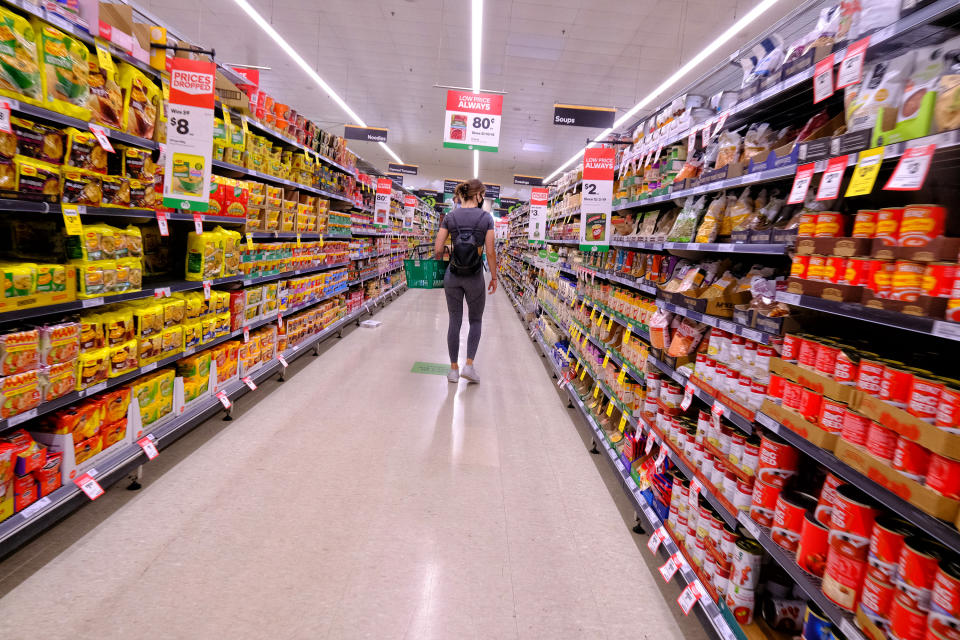 Pictured is a person walking down an aisle at a Woolworths supermarket.