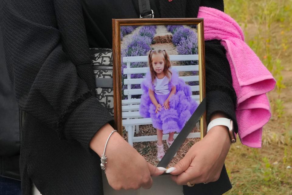 A woman carries a portrait of Liza, 4-year-old girl killed by Russian attack, during a funeral ceremony in Vinnytsia, Ukraine, on July 17, 2022. Liza was among 23 people killed, including two boys aged 7 and 8, in Thursday's missile strike in Vinnytsia. Her mother, Iryna Dmytrieva, was among the scores injured.