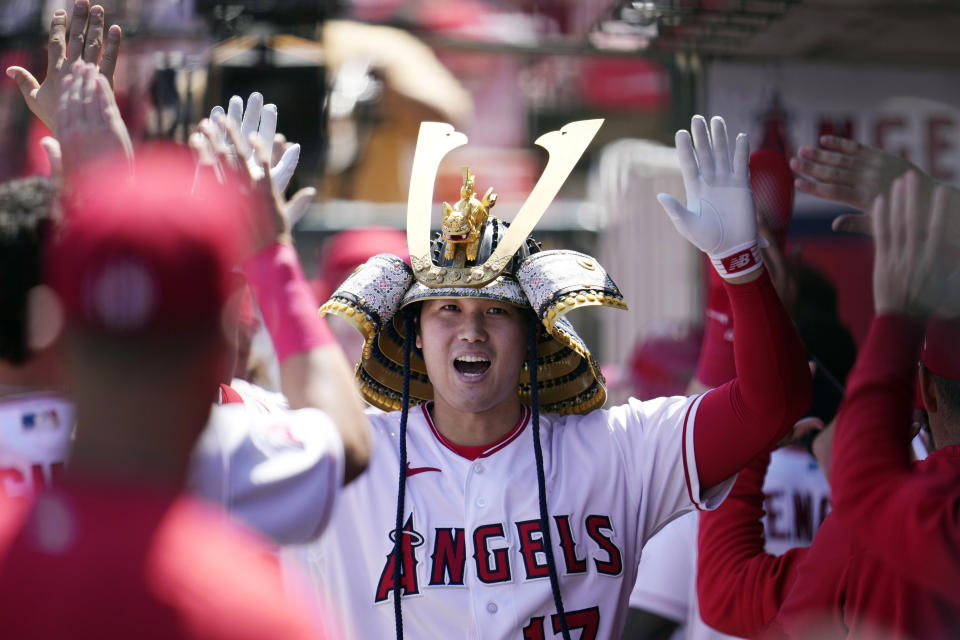 FILE - Los Angeles Angels' Shohei Ohtani, wearing a samurai helmet, is greeted in the dugout after two-run home run against the Toronto Blue Jays Sunday, April 9, 2023, in Anaheim, Calif. About half the clubs in MLB are using some kind of prop or ritual to celebrate a big hit or a big play in ways that often go viral. (AP Photo/Marcio Jose Sanchez, File)