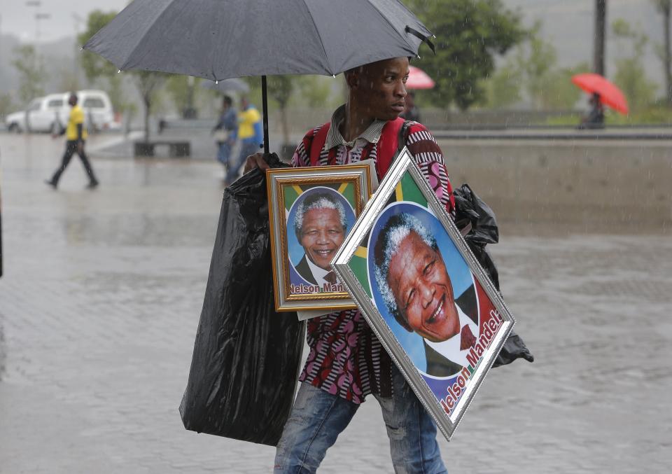 A man sells portraits of Nelson Mandela outside of the memorial service for former South African president Nelson Mandela at the FNB Stadium in Soweto, near Johannesburg, South Africa, Tuesday Dec. 10, 2013. (AP Photo/Tsvangirayi Mukwazhi)