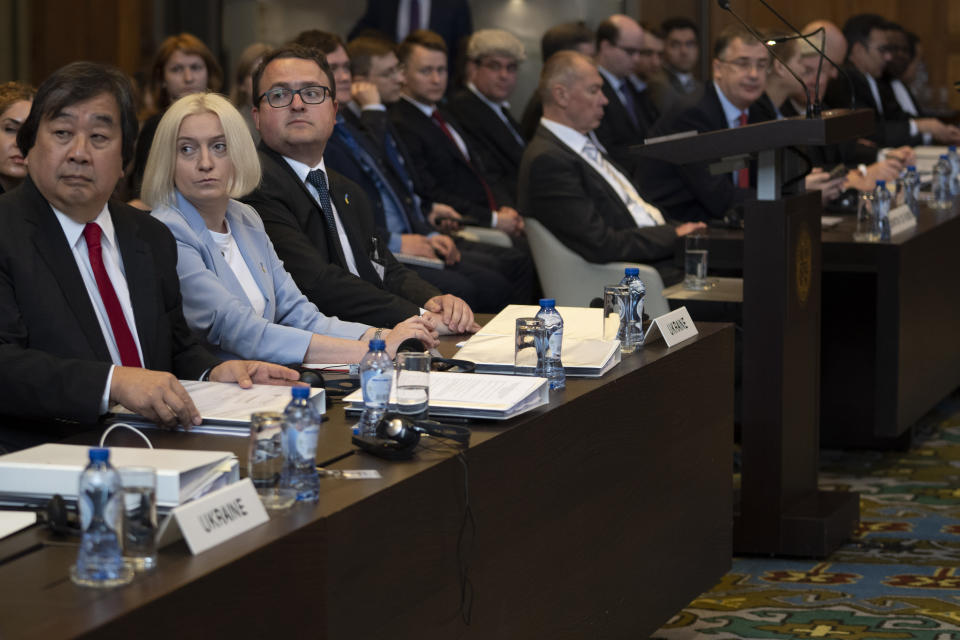 Ukraine's delegation with ambassador-at-large of the ministry of foreign affairs Anton Korynevych, third from left, and Russia's delegation with Gennnady Kuzmin, ambassador-at-large of the ministry of foreign affairs, bench on the right side, wait for judges to enter the World Court in The Hague, Netherlands, Tuesday, June 6, 2023. Four days of hearings open in a case brought by Ukraine against Russia at the UN's top court alleging that Russia breached treaties on terrorist financing and racial discrimination in eastern Ukraine and Crimea. (AP Photo/Peter Dejong)