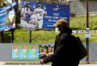 FILE - In this April 2, 2020, file photo, a pedestrian wears a hat and a face mask on Sunset Blvd., in the Echo Park neighborhood of Los Angeles. With no games being played, recent sports headlines have centered around hopes and dreams — namely, the uncharted path leagues and teams must navigate to return to competition in the wake of the pandemic. (AP Photo/Damian Dovarganes, File)