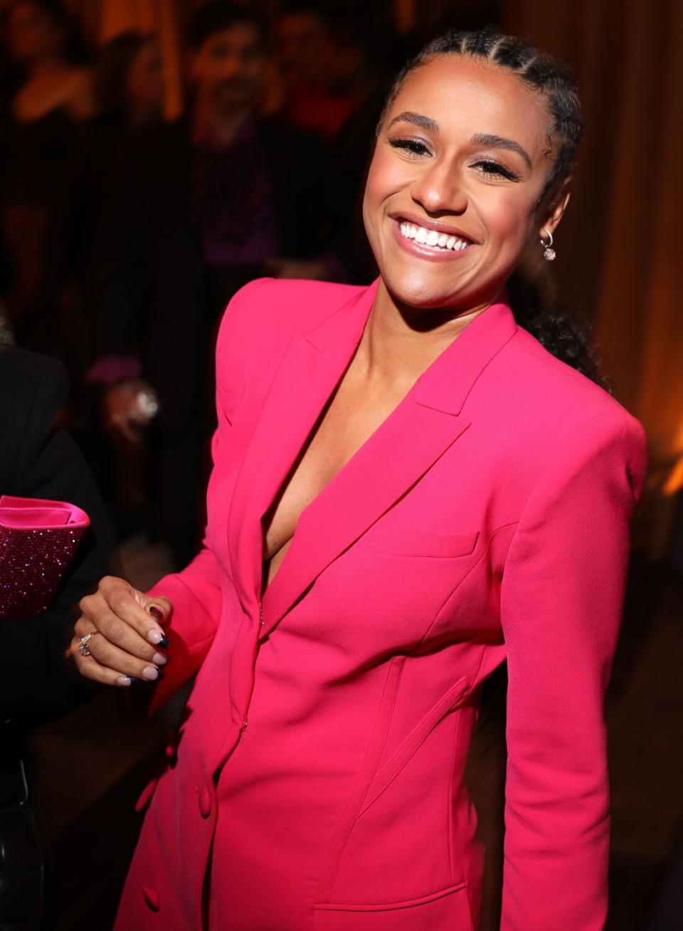 woman in a pink pantsuit smiles