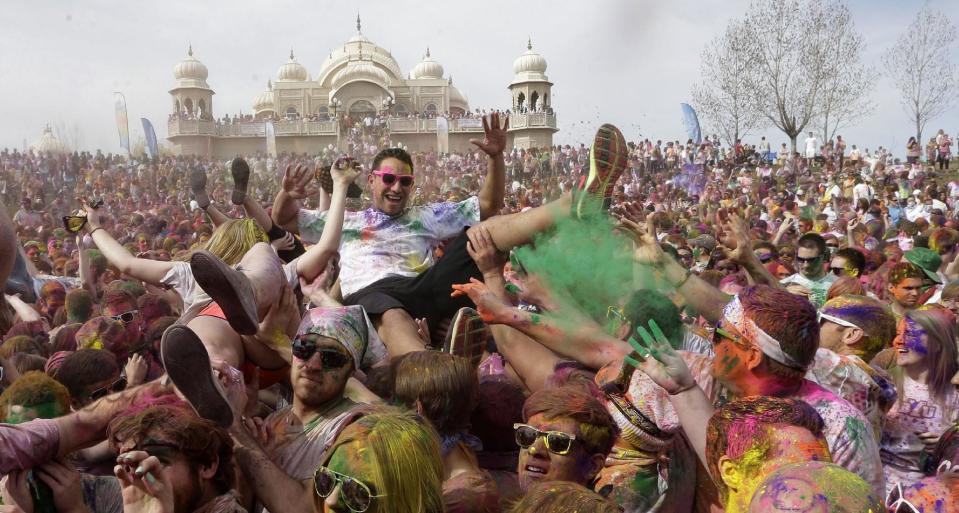 Revelers covered in colored corn starch celebrate during the 2014 Festival of Colors, Holi Celebration at the Krishna Temple Saturday, March 29, 2014, in Spanish Fork, Utah. Nearly 70,000 people are expected to gather starting Saturday at a Sri Sri Radha Krishna Temple in Spanish Fork for the annual two-day festival of colors. Revelers gyrate to music and partake in yoga during the all-day festival, throwing colored corn starch in the air once every hour. The Salt Lake Tribune reports that the large majority of participants are not Hindus, but Mormons. Thousands of students from nearby Brigham Young University come to take part in a festival that is drug and alcohol free. The event stems from a Hindu tradition celebrating the end of winter and the triumph of good over evil. (AP Photo/Rick Bowmer)