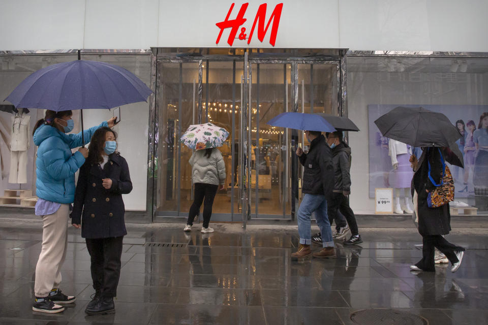 People walk past an H&M clothing store at a shopping mall in Beijing, Friday, March 26, 2021. H&M disappeared from the internet in China as the government raised pressure on shoe and clothing brands and announced sanctions Friday against British officials in a spiraling fight over complaints of abuses in the Xinjiang region. (AP Photo/Mark Schiefelbein)