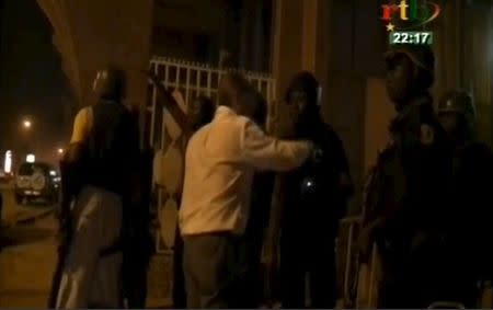 Security officers standing outside a building near Splendid Hotel in Ouagadougou where suspected Islamist fighters are holding hostages in this still image from a video grab, January 15, 2016. REUTERS/RTB via REUTERS TV