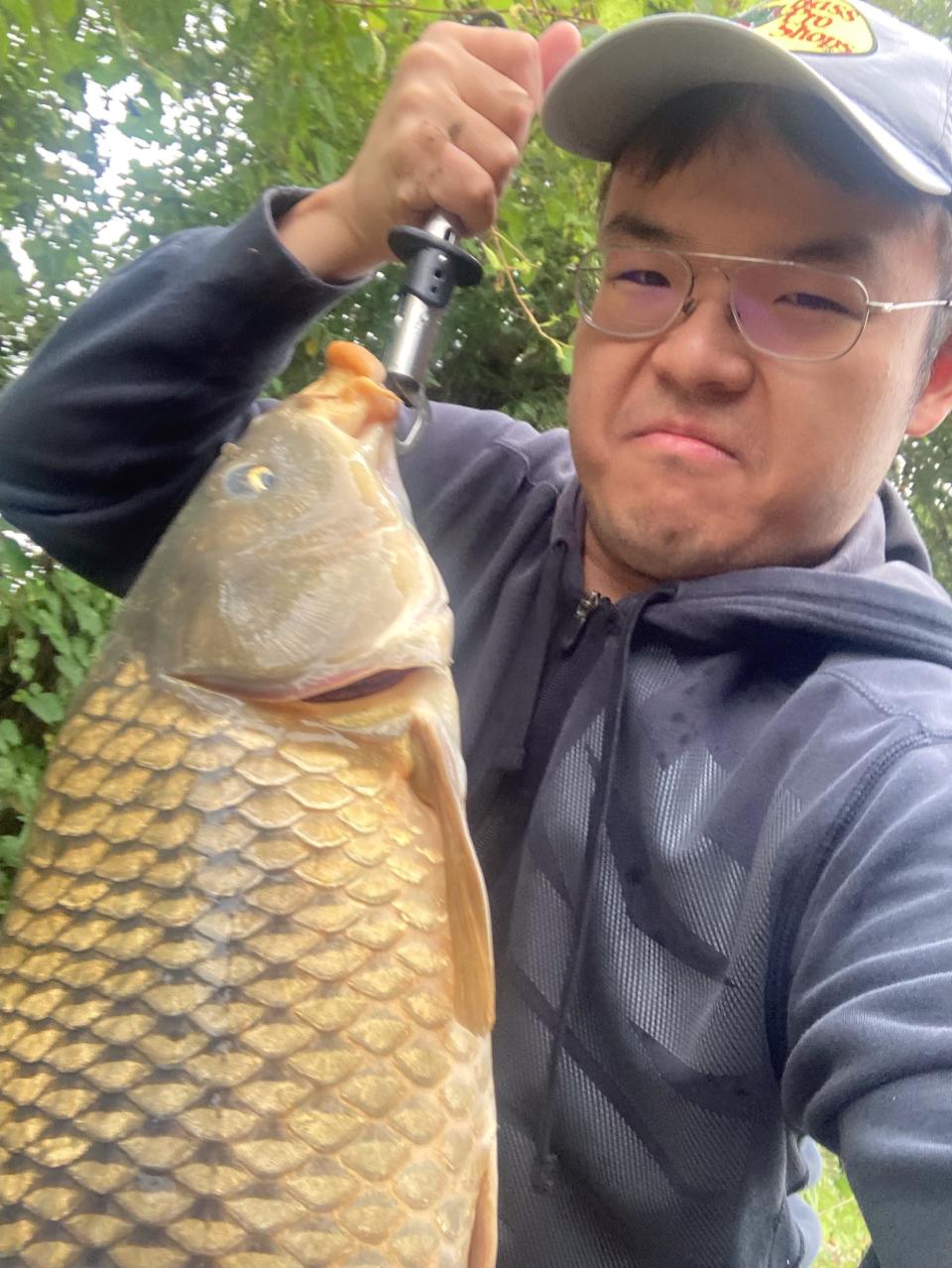 Liu He, here with a common carp he fished out of the Wabash River, won 15 Fish of the Year awards in 2022 through the Indiana Department of Natural Resources.