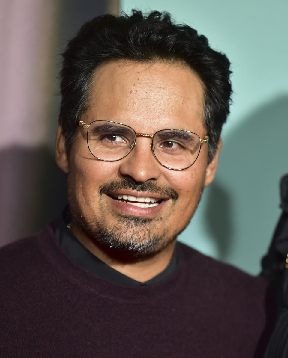 Michael Peña smiling and wearing glasses and a casual sweater at an event