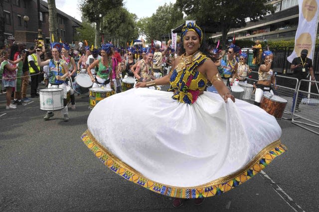 A woman in traditional dress spins to show here wide white skirt trimmed in braid 